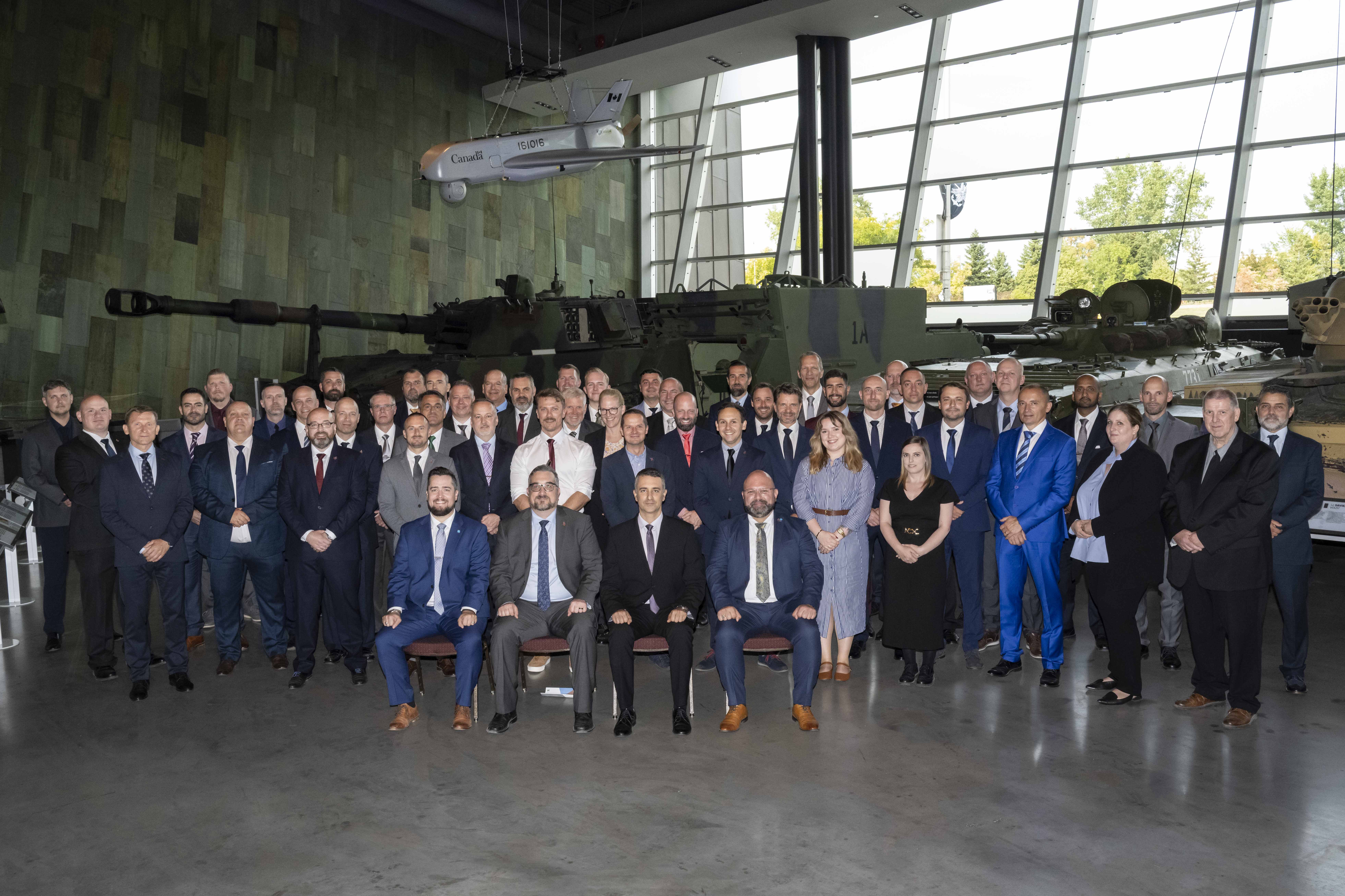  A large group of delegates from 21 nations pose for a formal group photo inside the Canadian War Museum . 