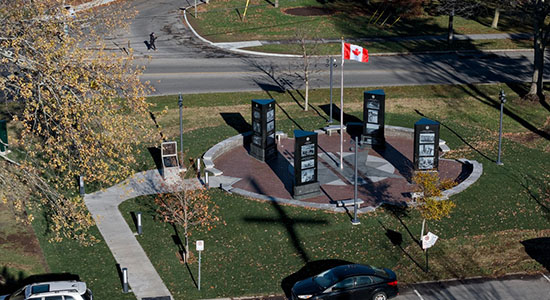 Outdoor memorial in a circle shape with four pillars and the Canadian flag in the middle.