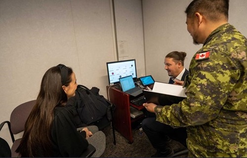 Three cyber personnel review simulated incident data on computer screens during a NATO exercise.