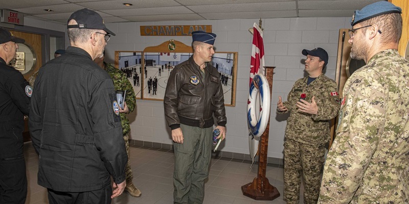 People in various military uniforms standing in a room and talking.