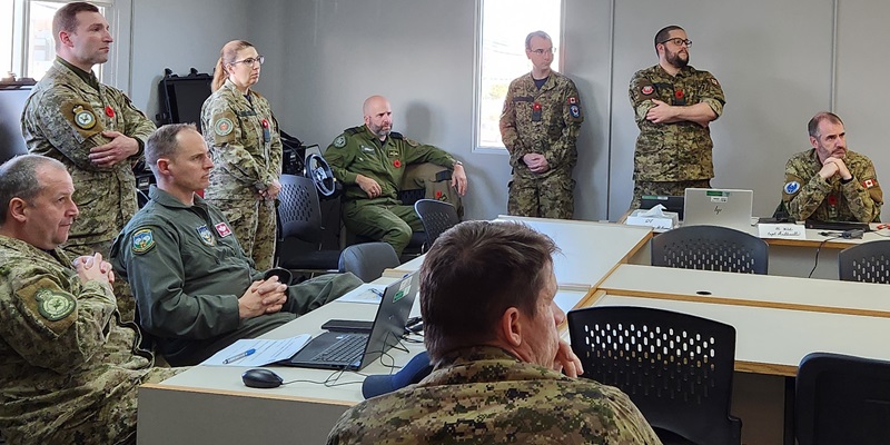 A group of people in military uniforms sitting and standing around a table.
