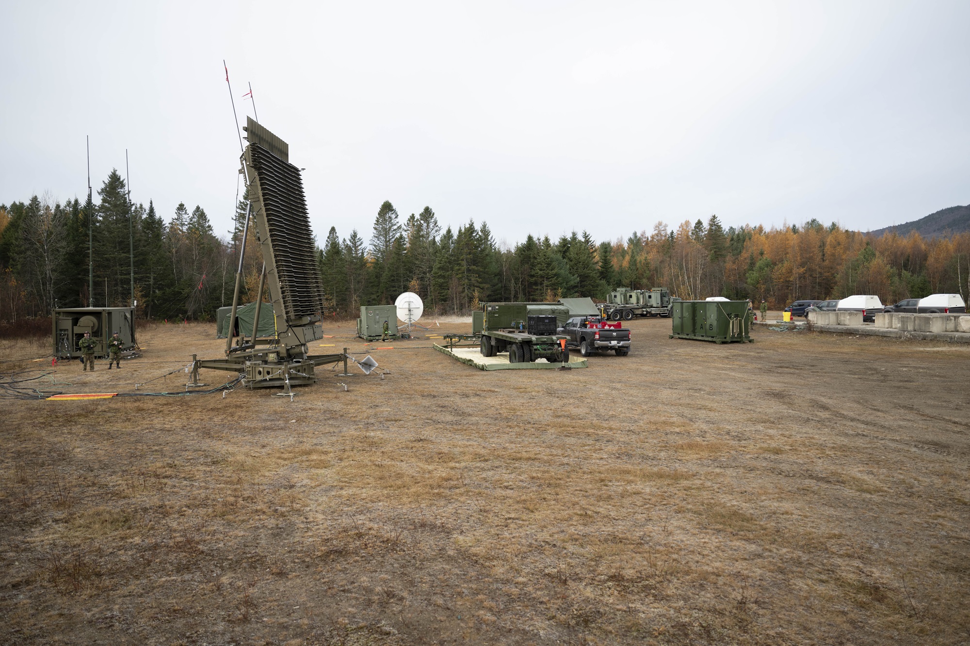 A field with military equipment and trees in the background.