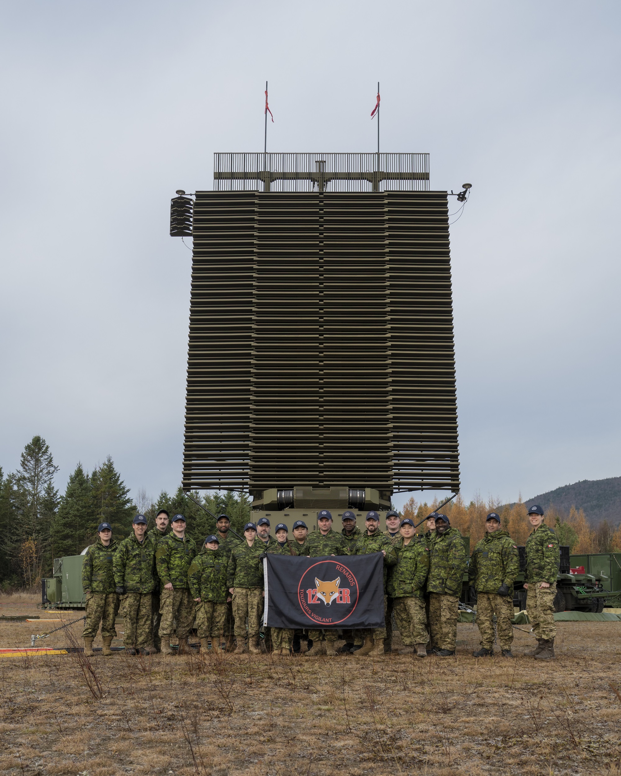 A group of people in military uniforms standing in front of a radar installation.