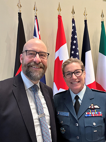 RCAF Commander and Assistant Deputy Minister (Policy) standing in front of international flags.