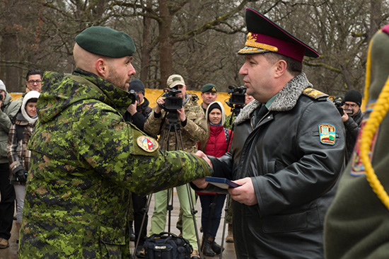 A Canadian soldier in uniform receives an award from a Ukrainian officer.