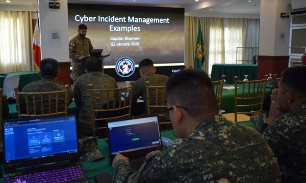 Un cyberinstructeur des Forces armées canadiennes présente un exposé sur la gestion des cyberincidents au personnel des Forces armées des Philippines assis devant des ordinateurs portables lors d'une formation dans une salle de conférence.