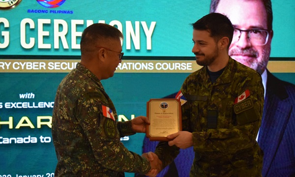 Un cyberofficier des Forces armées canadiennes reçoit une plaque de reconnaissance des mains d'un général de l'armée philippine lors de la cérémonie de clôture d'un cours sur les opérations de cybersécurité.