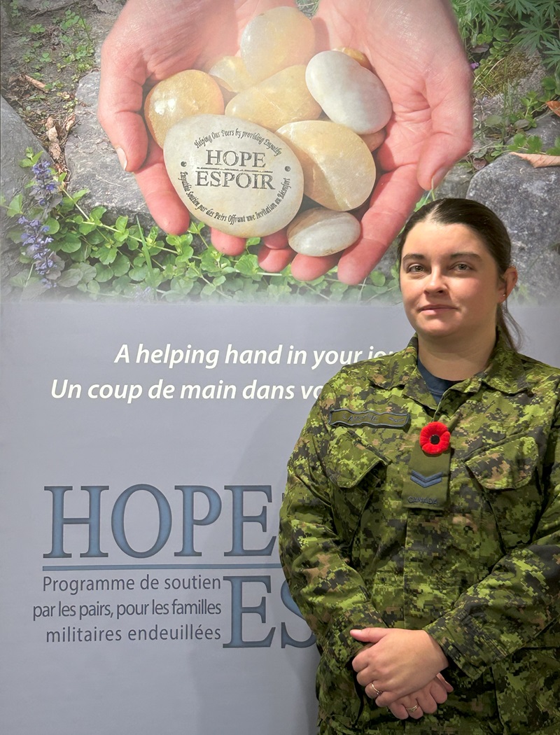 Corporal Nicole Lamothe is smiling and wears a green military uniform with the HOPE banner beside her.