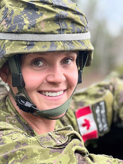 Canadian armed forces member outdoors in uniform and helmet with a Canadian flag patch.