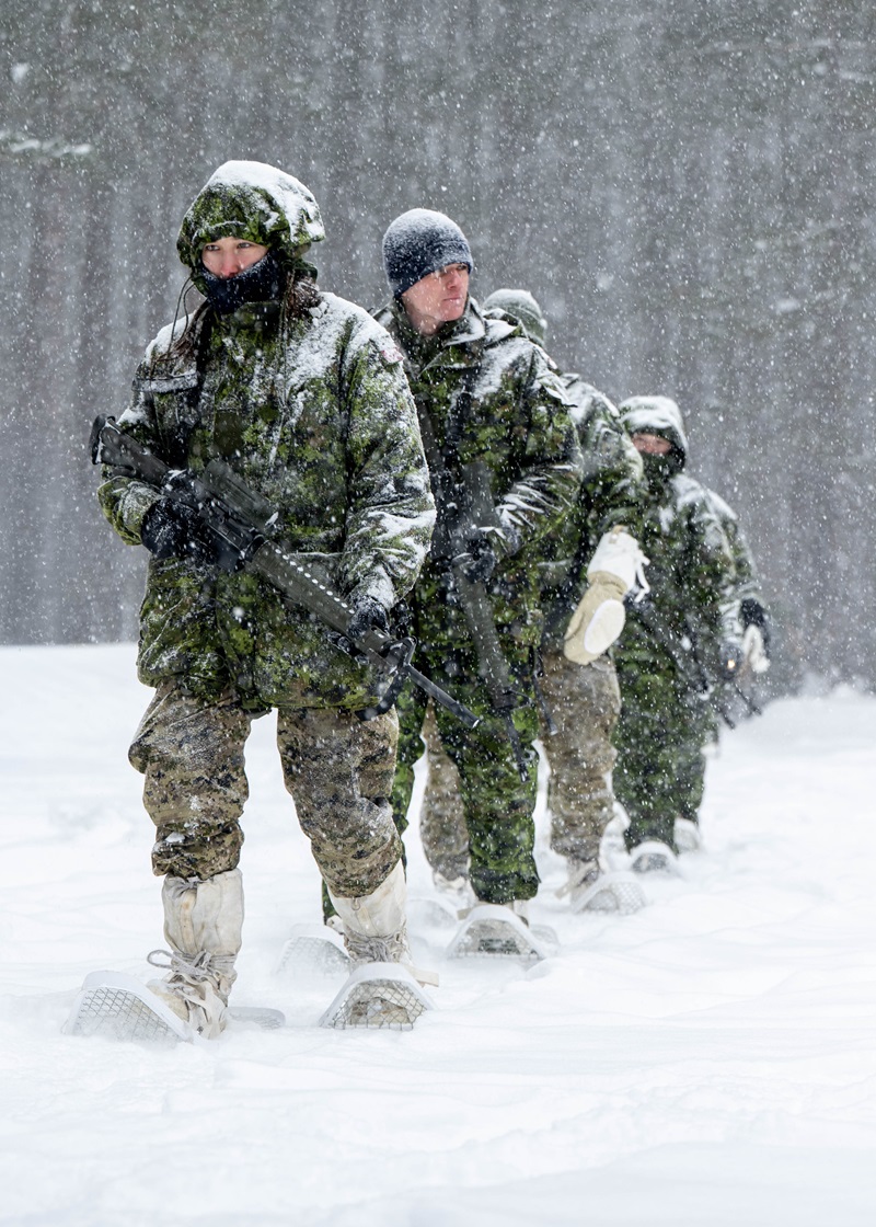 CAF members walking in a line through heavy snow during cold weather operator training.