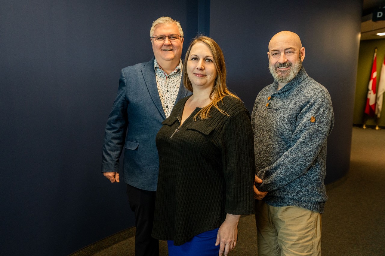 Three members of CAFCYBERCOM’s Command Evolution Team standing together in a headquarters hallway.