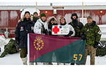 Members of the Canadian Armed Forces medical team pose outside Fort Eureka during NOREX 2026, holding a 57 Field Ambulance flag and a commemorative exercise sign in the High Arctic.