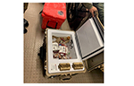 Portable refrigerated medical containers and insulated transport equipment used for blood and temperature-sensitive medical supplies are displayed beside a patient transport stretcher.