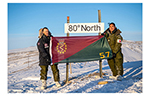 Two Canadian Armed Forces medical personnel hold a 57 Field Ambulance flag beside an “80° North” sign during NOREX 2026 in the High Arctic.