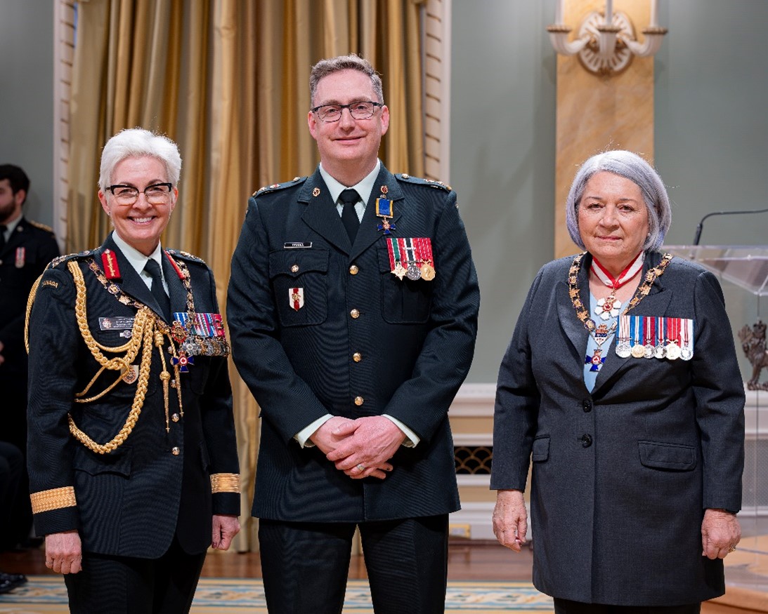 Three people are standing side-by-side at an award ceremony and smiling at the camera.