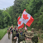 Des marcheurs des FAC portent des drapeaux canadiens pendant la marche de validation au Luxembourg.