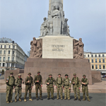 Des membres de la Force opérationnelle Lettonie se tiennent devant un monument après la marche.