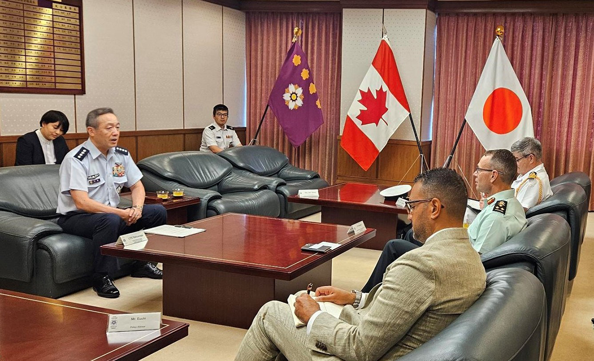 Lieutenant-General Derek Macaulay sits across from senior leaders of the Japan Self-Defense Forces during a meeting in Tokyo. Canadian, Japanese and JSDF flags are displayed behind the participants as they discuss defence cooperation and regional security.