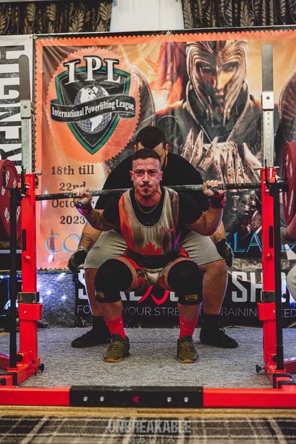 A soldier performs a squat with a heavy weight.