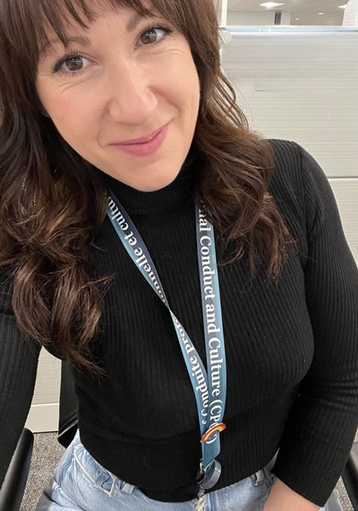 A woman wearing a lanyard poses for a selfie.