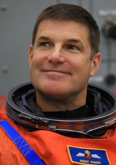 A close-up featuring the face of a Canadian astronaut wearing a space suit without a helmet.
