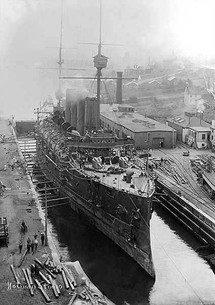 A ship sitting at a dock, surrounded by servicemen and their materials.