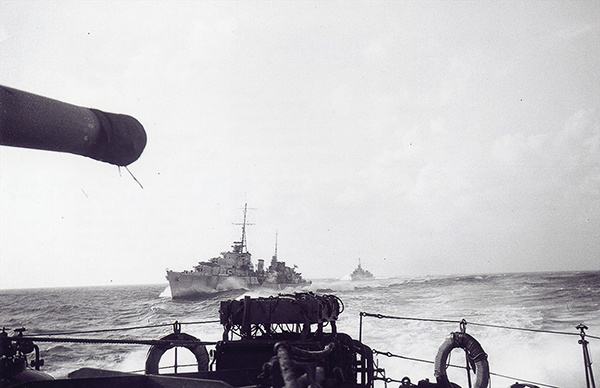 Two ships are seen from the perspective of another ship on the water.