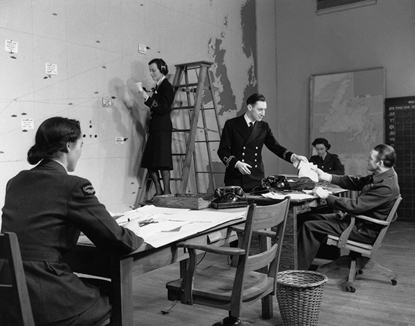 Men and women in uniform work diligently in the combined operations room.