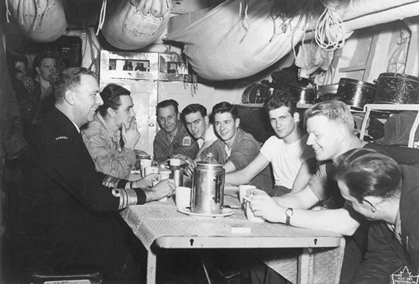 Naval personnel sitting around a table enjoying conversation.