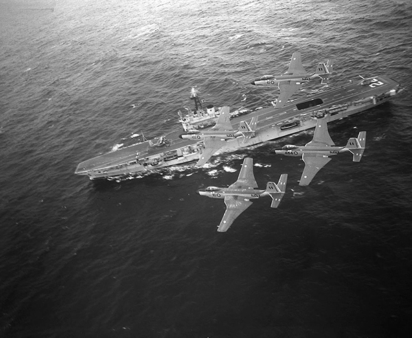 Three aircraft fly over a naval ship.