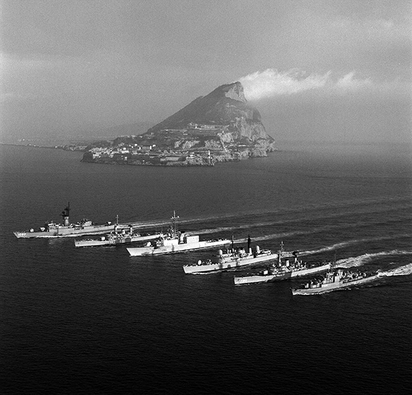 Six ships travel side by side on the water.
