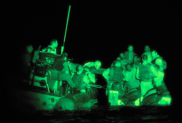 Two rafts travel side by side carrying CAF personnel as well as a group of men whose faces are blurred out.
