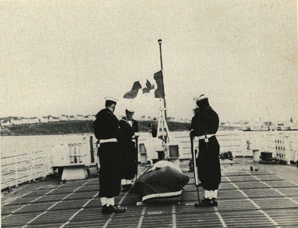 Four sailors and a coffin on the deck of the ship.