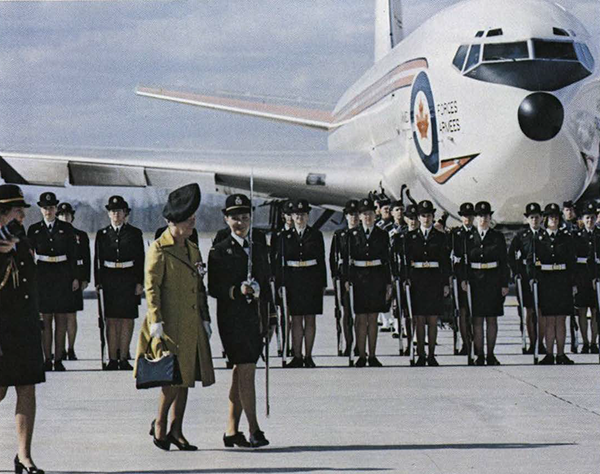 Female soldiers at attention, in front of a plane.