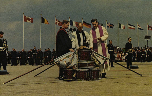 Clergymen with flags lowered over drums.