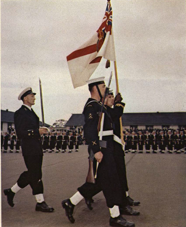 Soldiers at atttention, one of them carrying a flag.