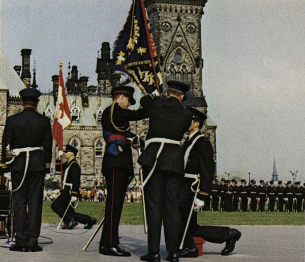 Soldiers with a flag in front of Parliament Hill.