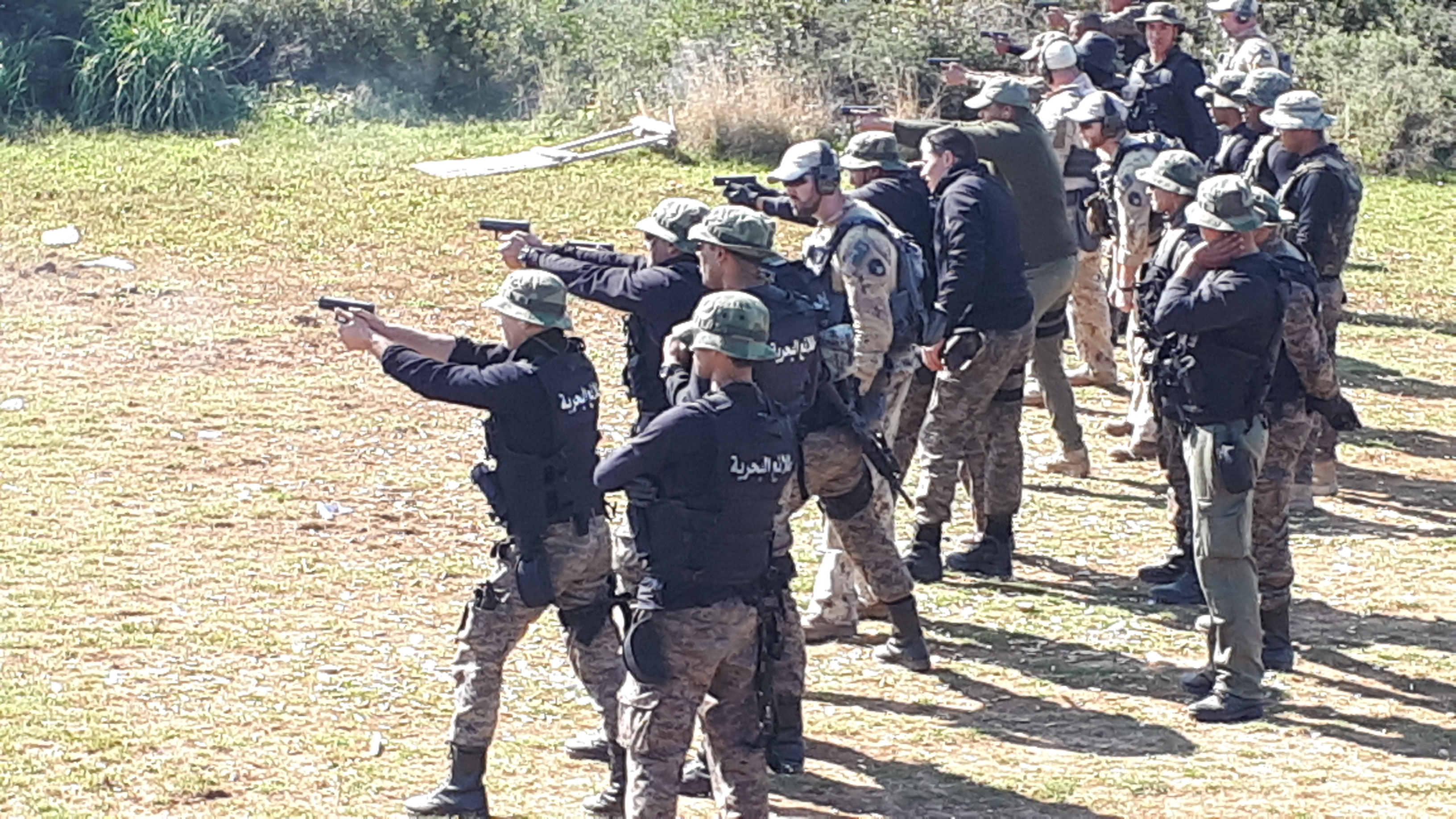 Military members fire weapons on a range.