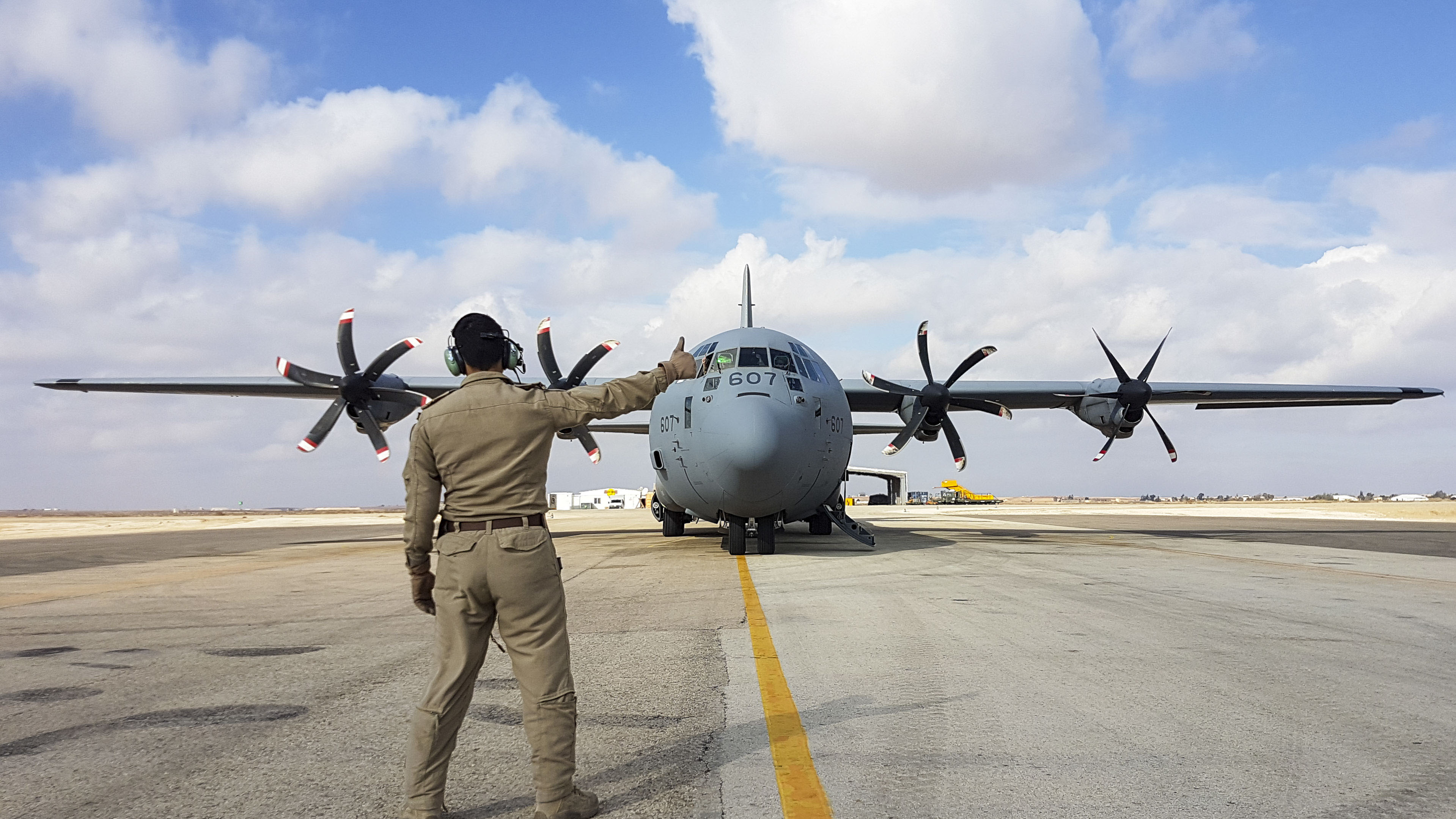 A Canadian Armed Forces member signals the all clear to the Co-Pilot, so that he can start the engines of the CC130-J Hercules aircraft prior to leaving an airfield in Jordan to travel back to Kuwait, 28 December 2018. Image by:  Op IMPACT Imaging