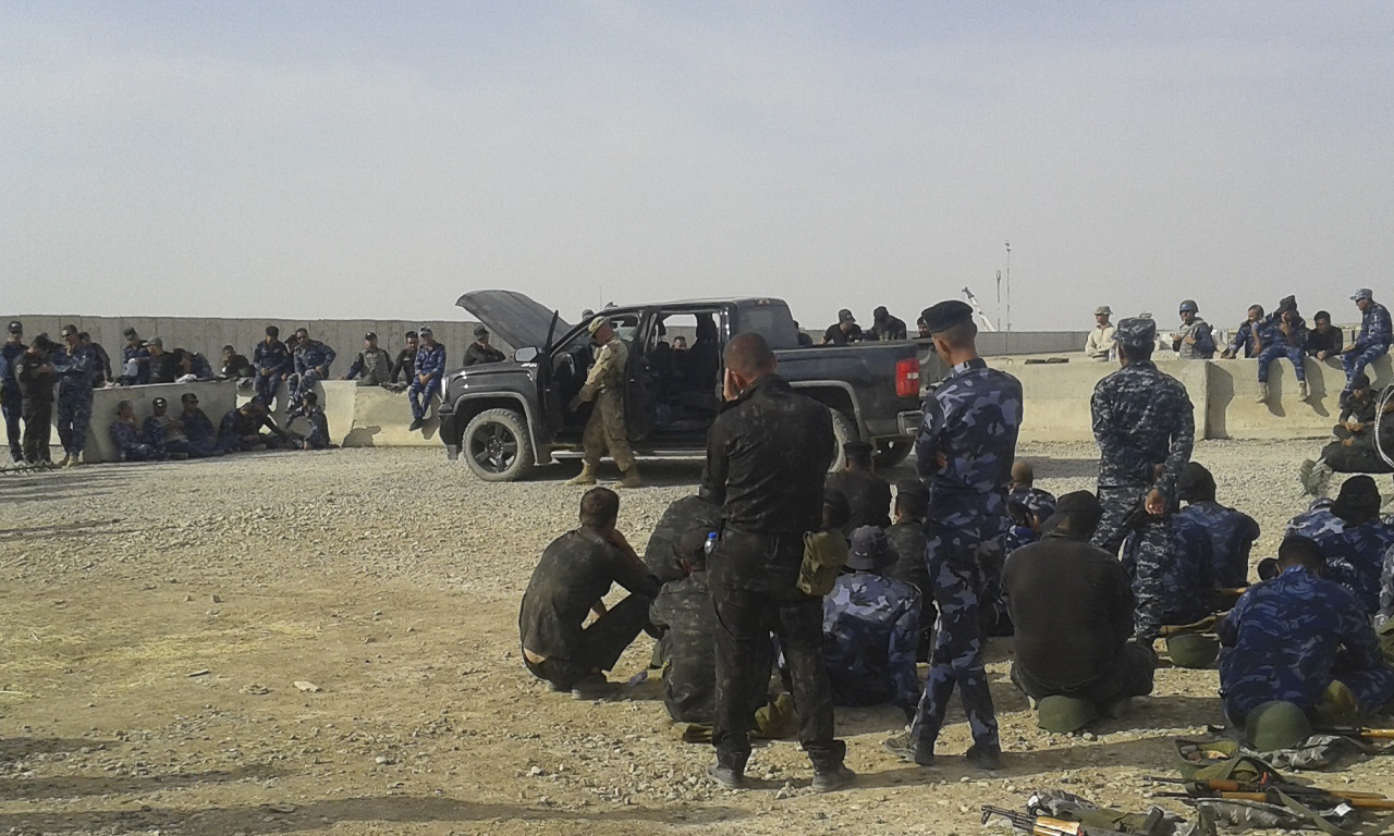 Des membres des Forces de sécurité irakiennes observent les instructeurs des Forces armées canadiennes faire la démonstration d’une fouille de véhicule, au centre d’instruction de Q-Ouest, le 3 août 2018. Photo : Services d’imagerie de l’Op IMPACT