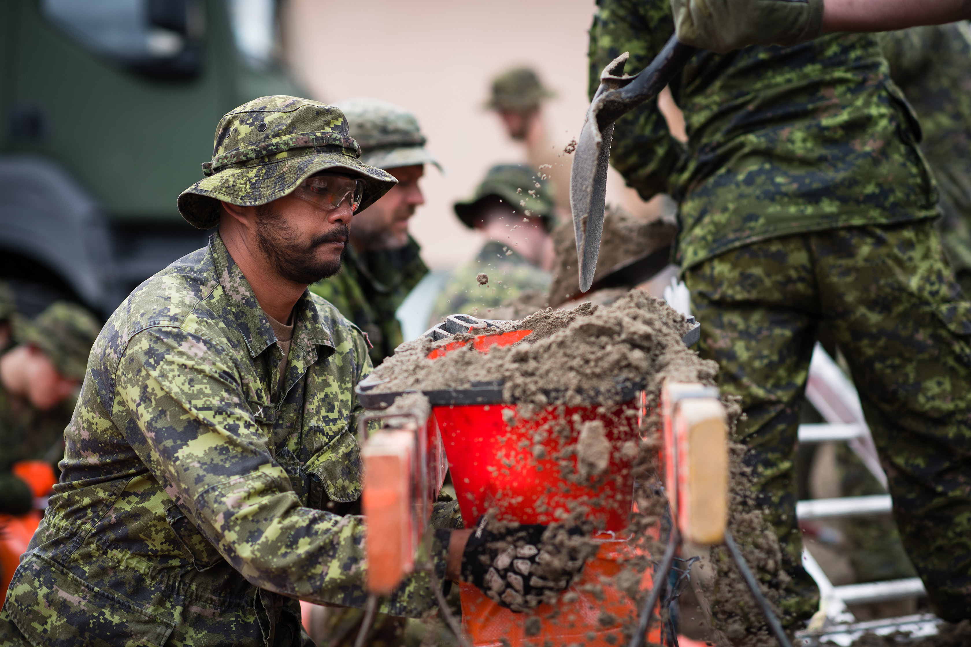Des membres des Forces armées canadiennes déplacent et remplissent des sacs de sable pour lutter contre l’arrivée de l’eau des crues à Gatineau, au Québec, dans le cadre de l’opération LENTUS, le 24 avril 2019.