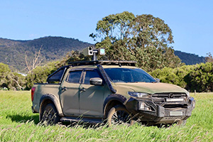 A counter-drone device mounted on top of a truck with trees in the background.