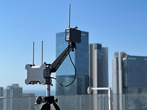 A close-up of a drone antenna with buildings in the background.