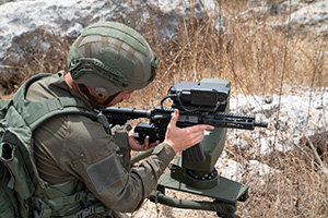 A person in military uniform aiming a counter-drone device.