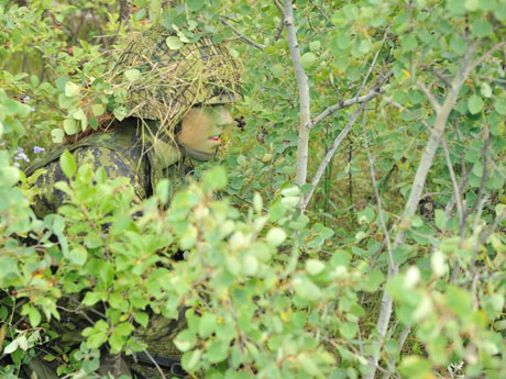 A recruit utilizing camouflage and concealment during the field training exercise.