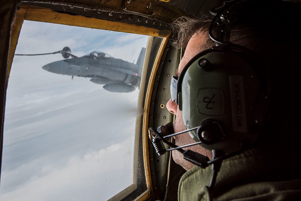 Warrant Officer Ron Demchuk, a loadmaster with 435 Transport and Rescue Squadron,watches as a CF-188 Hornet refuels from a CC-130J Hercules aircraft during Operation NANOOK over the coast of Labrador on August 20, 2017.Photo: Corporal Anthony Laviolette, 12 Wing Imaging Services, N.S