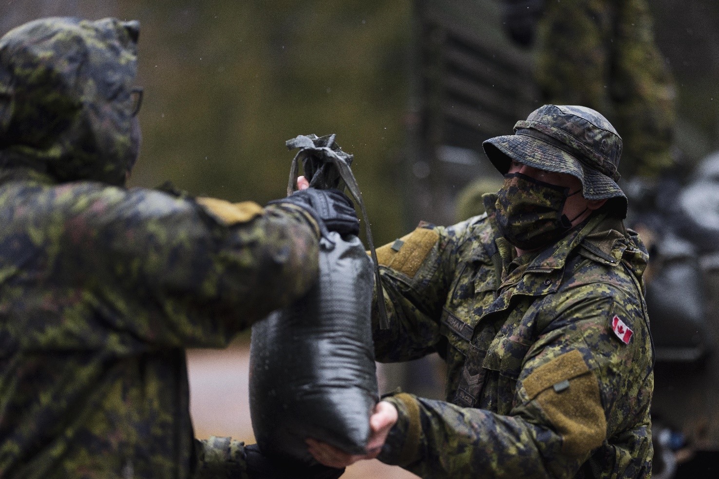 Two soldiers filling bags of sand.