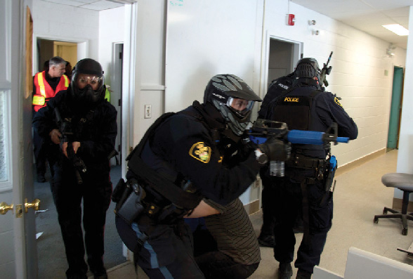Police officers entering a room, armed.