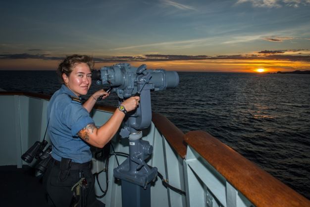 Leading Seaman Kayla Ruiz uses the Big Eyes on Her Majesty's Canadian Ship (HMCS) WINNIPEG as the ship departs the Philippines, April 18, 2017.