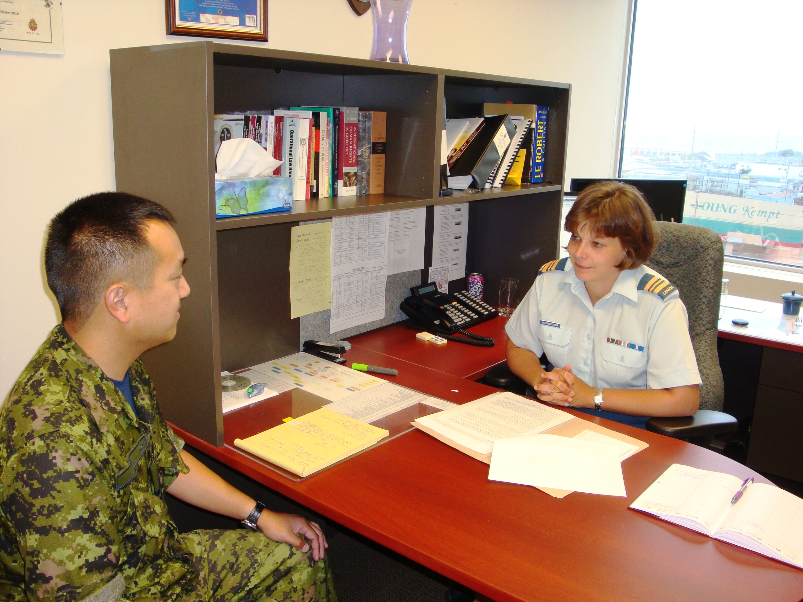 Un avocat militaire discute avec un client dans son bureau.